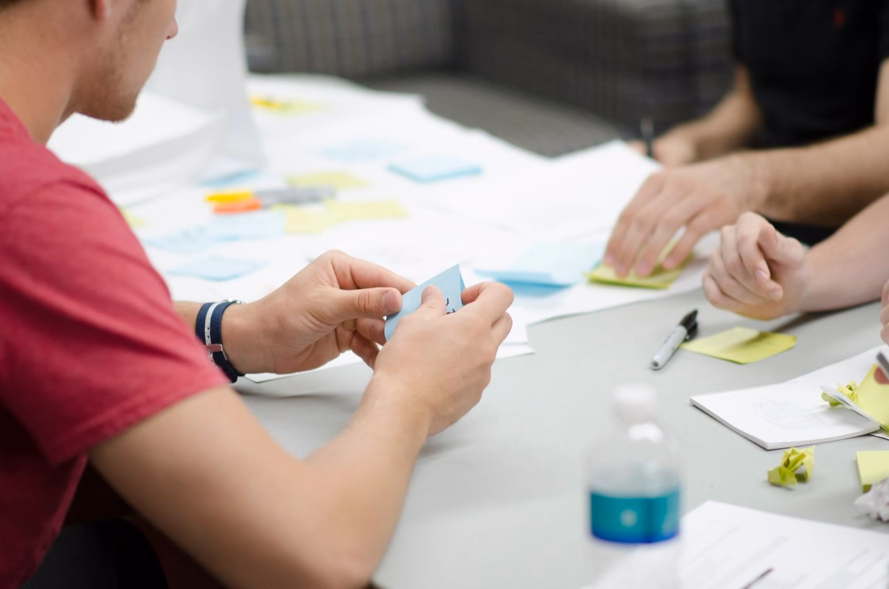 Collaborative workspace with people brainstorming using sticky notes, emphasizing teamwork and planning.